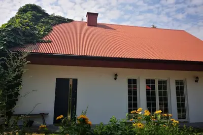 a white house with an orange roof and flowers at Lawenda i Bluszcz in Jankowice