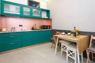 a kitchen with green cabinets and a wooden table at LUXURY Apartment at the Main Square Tomasza street in Kraków