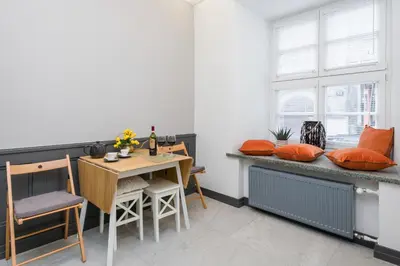a dining room with a table and a bench with orange pillows at LUXURY Apartment at the Main Square Tomasza street in Kraków