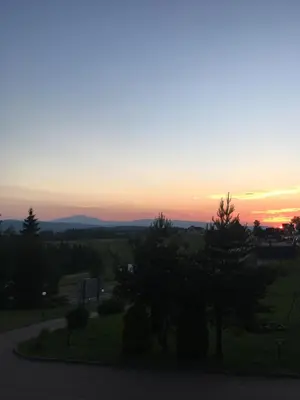 a sunset over a field with trees in the foreground at Hotel Restauracja U Guta in Klikuszowa