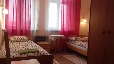 a bedroom with two beds and a window with pink curtains at Hostel Retro in Kraków