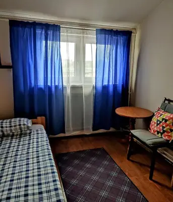 a bedroom with blue curtains and a table and a window at Hostel Retro in Kraków