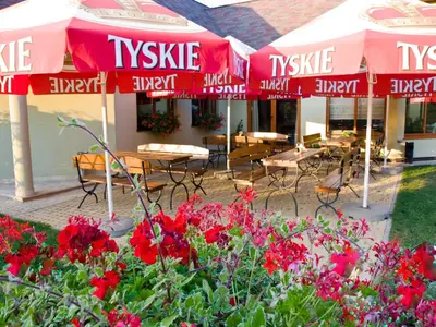 a patio with tables and chairs and umbrellas and flowers at Hotel Kochanów in Kochanów