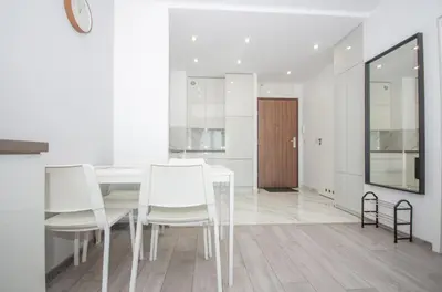 a white dining room with white chairs and a table at InPoint Zablocie Modern Apartments for Work&Travel Self Check-in in Kraków