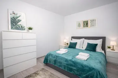 a white bedroom with a bed with two towels on it at InPoint Zablocie Modern Apartments for Work&Travel Self Check-in in Kraków