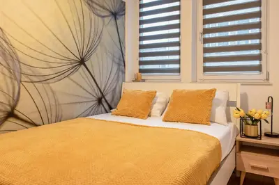 a bedroom with a bed with yellow sheets and windows at 3D KOSCIUSZKI 19 Apartament in Kraków