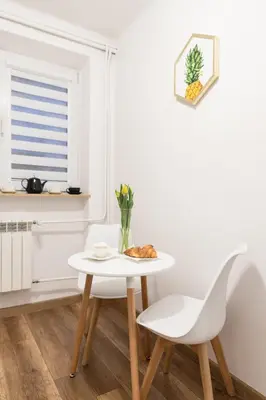 a white kitchen with a white table and chairs at Szmaragd in Rabka
