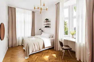 a white bedroom with a bed and a chair at Wesoła by Landmark Apartments in Kraków