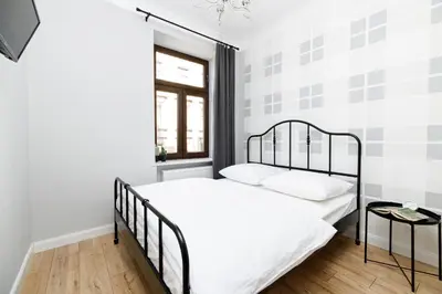 a bedroom with a bed with white sheets and a window at Native Apartments Blich 7 in Kraków