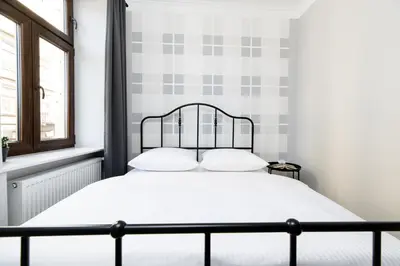 a bedroom with a bed with white sheets and a checked wall at Native Apartments Blich 7 in Kraków