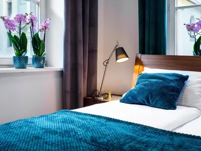a bedroom with a bed with a blue blanket and flowers at CracWoW St. Thomas Apartment in Kraków