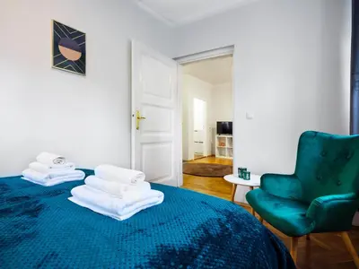a bedroom with a blue bed and a green chair at CracWoW St. Thomas Apartment in Kraków