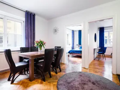 a dining room with a table and chairs and a bedroom at CracWoW St. Thomas Apartment in Kraków