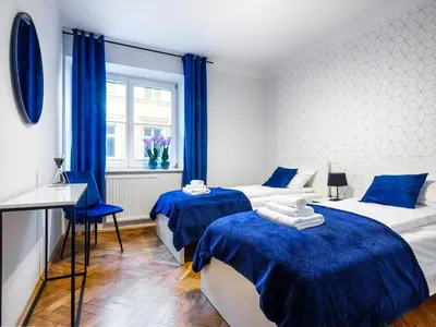 two beds in a room with blue curtains at CracWoW St. Thomas Apartment in Kraków