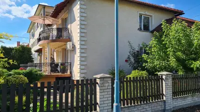 a house with a fence next to a house with an umbrella at Apartament DeLuxe 1 in Oświęcim
