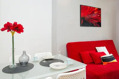 a living room with a red couch and a table with a red flower at Apartament Amaryllis in Kraków