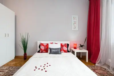 a bedroom with a white bed with red pillows at Apartament Amaryllis in Kraków