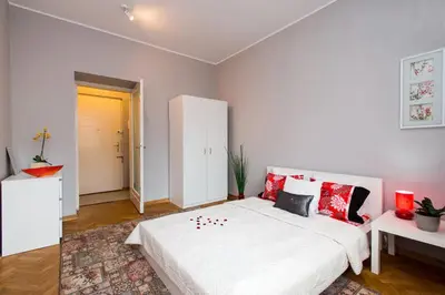 a bedroom with a large white bed with red pillows at Apartament Amaryllis in Kraków