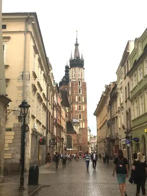 a group of people walking down a street with a clock tower at Apartament Amaryllis in Kraków