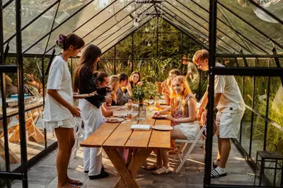 a group of people sitting around a table in a greenhouse at Zacisze in Morawica
