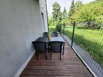 a table and chairs on a deck with a fence at Lion Apartment in Andrychów