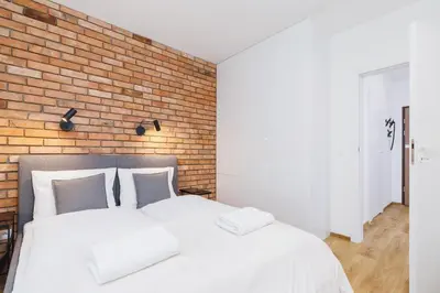 a bedroom with two white beds and a brick wall at Apartments Supernova near Tauron Arena by Noclegi Renters in Kraków