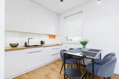 a kitchen with white cabinets and a table and chairs at Apartments Supernova near Tauron Arena by Noclegi Renters in Kraków