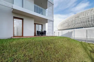a building with a grassy yard next to a building at Apartments Supernova near Tauron Arena by Noclegi Renters in Kraków