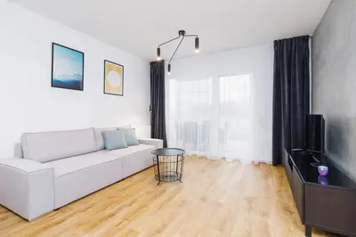 a living room with a white couch and a television at Apartments Supernova near Tauron Arena by Noclegi Renters in Kraków