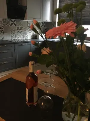 a bottle of wine sitting next to a vase with a glass at Apartamenty Centrum in Andrychów