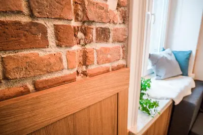 a brick wall next to a window with a pillow at Tower Street Apartments in Kraków