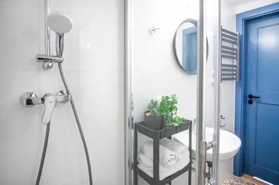 a bathroom with a shower with a mirror and a sink at Tower Street Apartments in Kraków