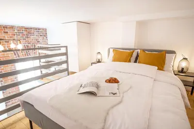 a white bed with a book and a plate of food on it at Tower Street Apartments in Kraków