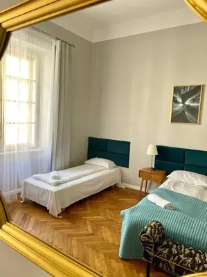 a reflection of a bedroom with two beds and a mirror at Floriańska Grand Apartment 2 in Kraków