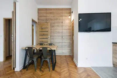 a dining room with a table and chairs and a flat screen tv at Fancy Apartments with Lift and A/C in Kraków