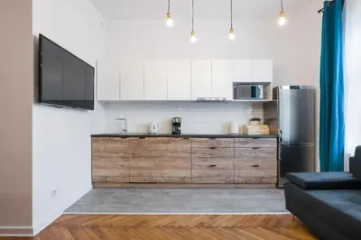 a kitchen with white cabinets and a stainless steel refrigerator at Fancy Apartments with Lift and A/C in Kraków