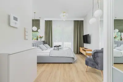 a white bedroom with a bed and a chair at Apartments Old Town Rakowicka by Noclegi Renters in Kraków