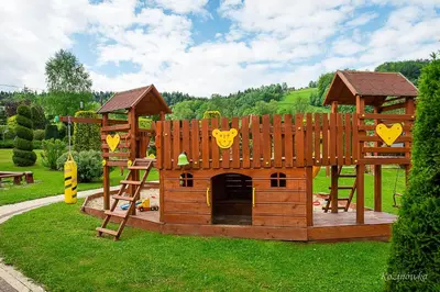 a playground with a wooden play structure in the grass at Kozinówka in Zawoja