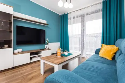a blue living room with a blue couch and a tv at City of the Kings - Wolf Apartment in Kraków