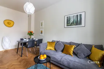 a living room with a gray couch with yellow pillows at Brokilon House in Kraków