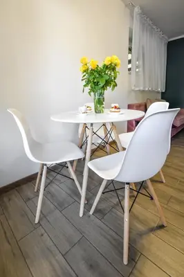 a white table and chairs with a vase of yellow flowers at Noclegi u Majki in Zator