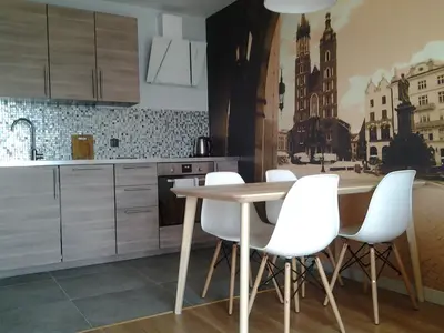 a kitchen with a table and white chairs at Garden Corner in Kraków