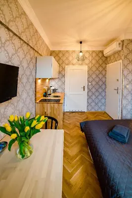 a kitchen with a table with a vase of flowers on it at Słowackiego Apartments in Kraków