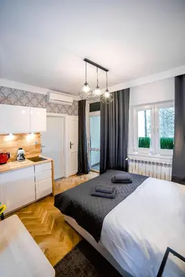 a bedroom with a large bed and a kitchen at Słowackiego Apartments in Kraków