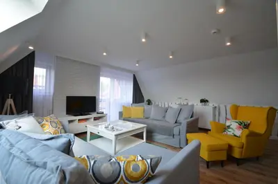 a living room with blue couches and yellow chairs at Willa Wiesia Rabka Zdrój in Rabka