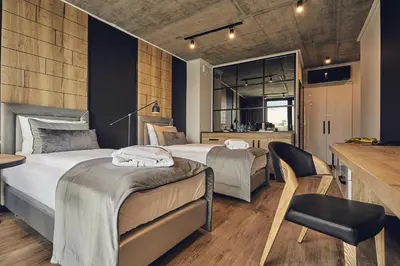 a bedroom with two beds and a table and a chair at The Bridge Suites Hotel in Kraków