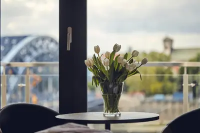 a vase of flowers on a table in front of a window at The Bridge Suites Hotel in Kraków