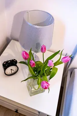 a vase of pink flowers on a table with a clock at Kopalnia Snów in Wieliczka