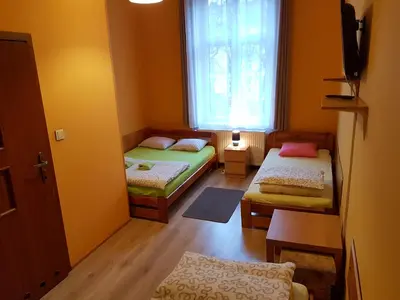a small room with two beds and a window at Dream Hostel & Apartments in Kraków