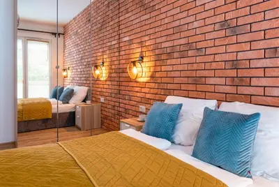a bedroom with a brick wall and a bed with blue pillows at Marvels Place with parking and AC in Kraków